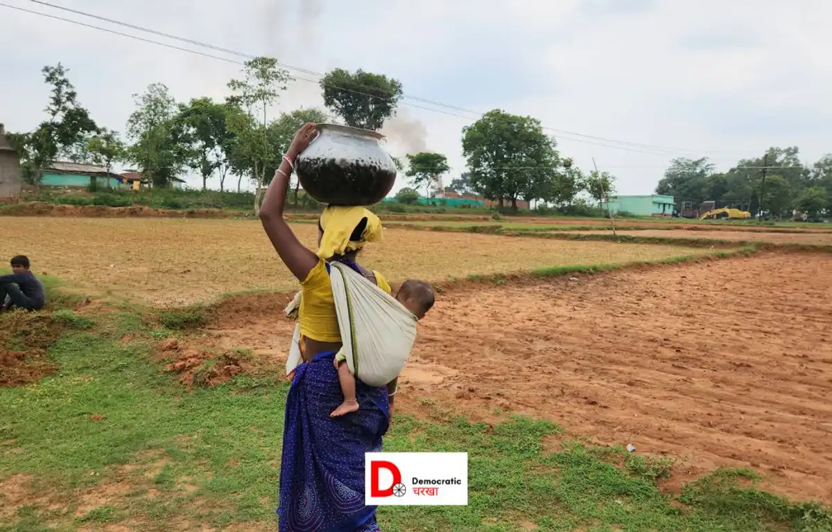 पीठ पर बच्चा, सर पर भारी बर्तन लेकर चलती महिला  